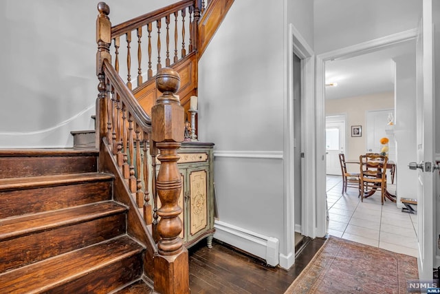 staircase with hardwood / wood-style floors and a baseboard heating unit