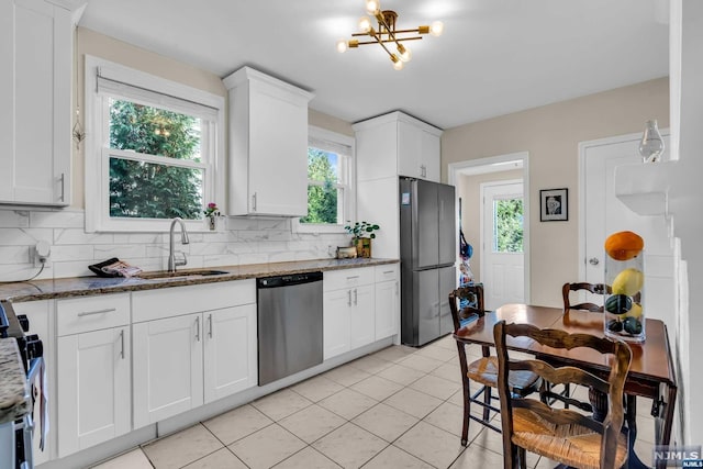 kitchen featuring white cabinets, appliances with stainless steel finishes, backsplash, and dark stone counters