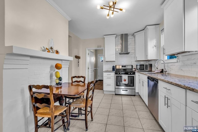 kitchen featuring light stone countertops, wall chimney exhaust hood, stainless steel appliances, sink, and white cabinetry