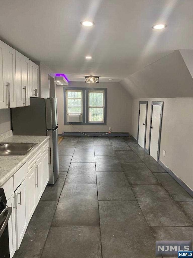 kitchen with appliances with stainless steel finishes, white cabinetry, lofted ceiling, and sink