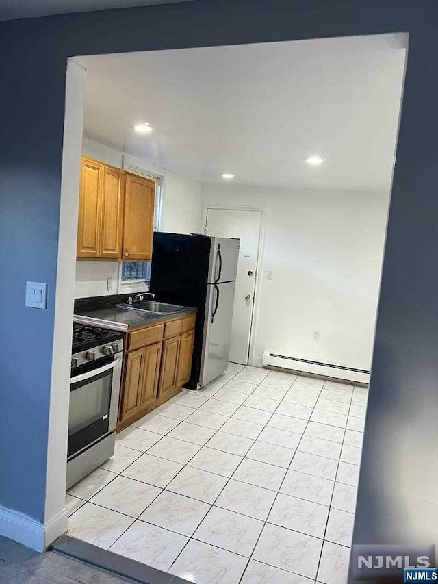 kitchen featuring baseboard heating, sink, light tile patterned floors, and stainless steel appliances