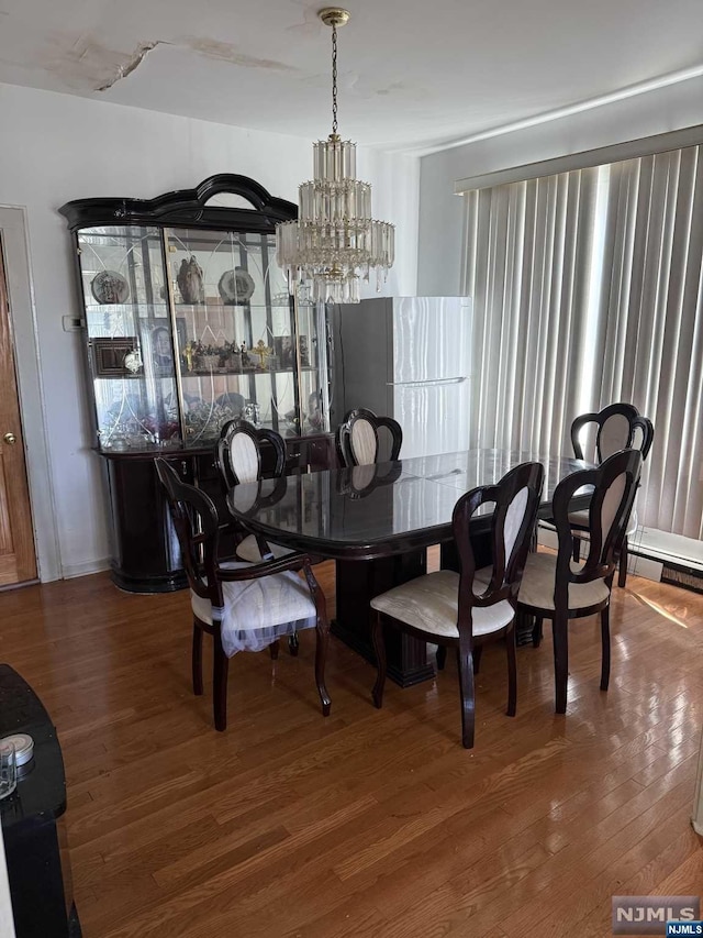 dining area with hardwood / wood-style floors and a notable chandelier