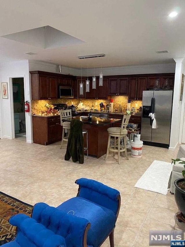 kitchen with a center island, hanging light fixtures, decorative backsplash, ornamental molding, and appliances with stainless steel finishes