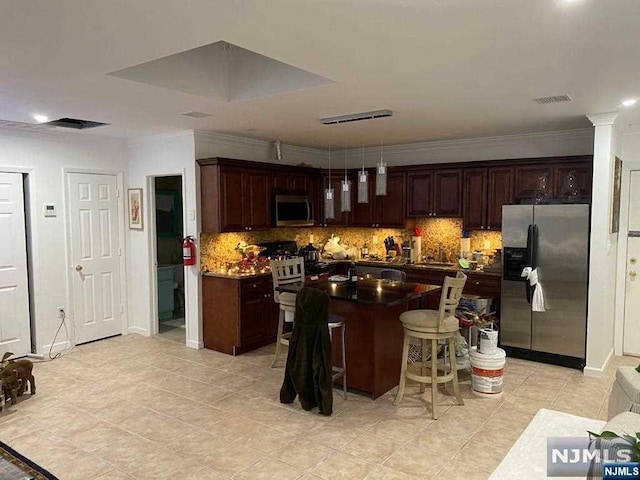 kitchen with a kitchen breakfast bar, appliances with stainless steel finishes, decorative backsplash, a kitchen island, and ornamental molding