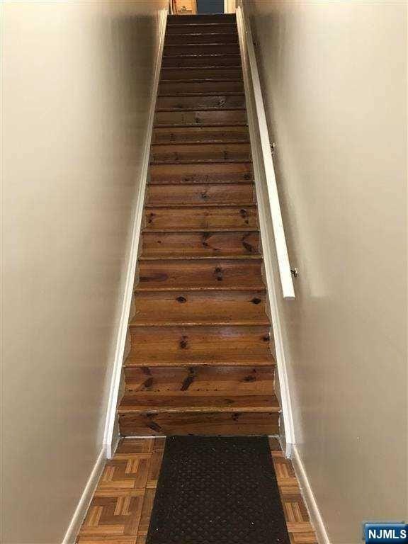 stairway featuring parquet flooring