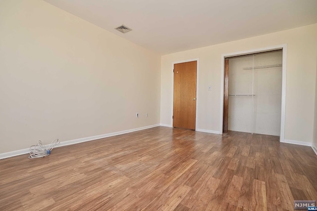 unfurnished bedroom featuring hardwood / wood-style floors and a closet