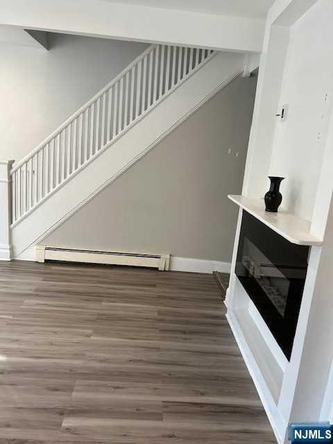 stairway with hardwood / wood-style floors and a baseboard radiator