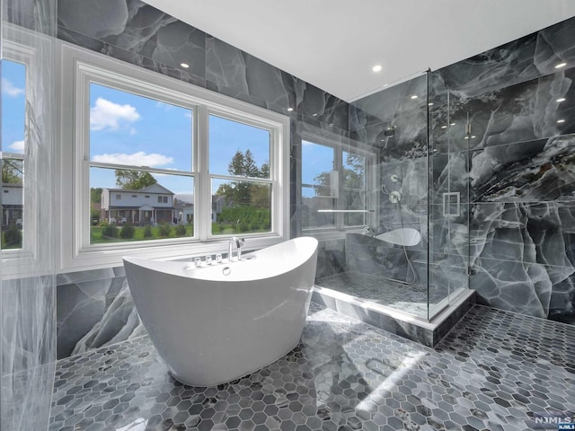 bathroom featuring plus walk in shower and tile walls