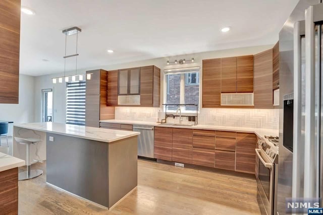 kitchen with a center island, sink, light hardwood / wood-style flooring, a wealth of natural light, and stainless steel appliances