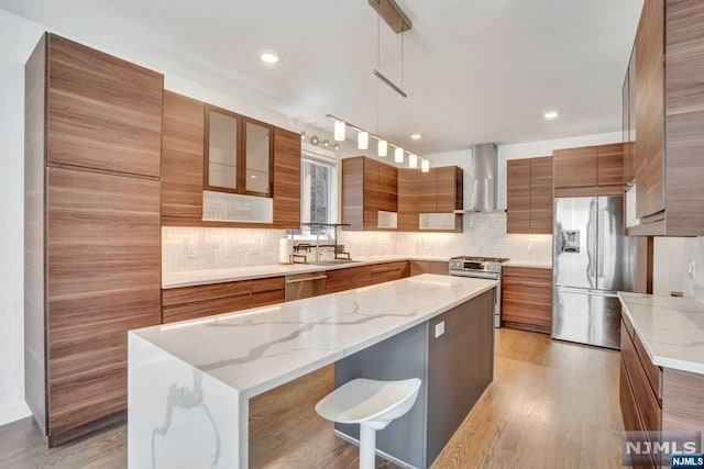 kitchen with a center island, light wood-type flooring, stainless steel appliances, and hanging light fixtures