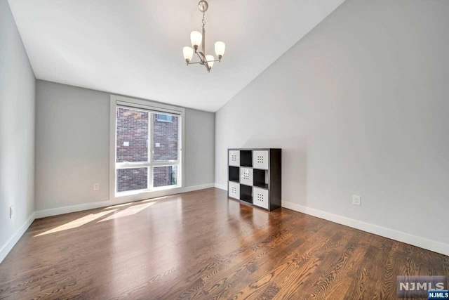 spare room featuring a chandelier, dark hardwood / wood-style flooring, and vaulted ceiling