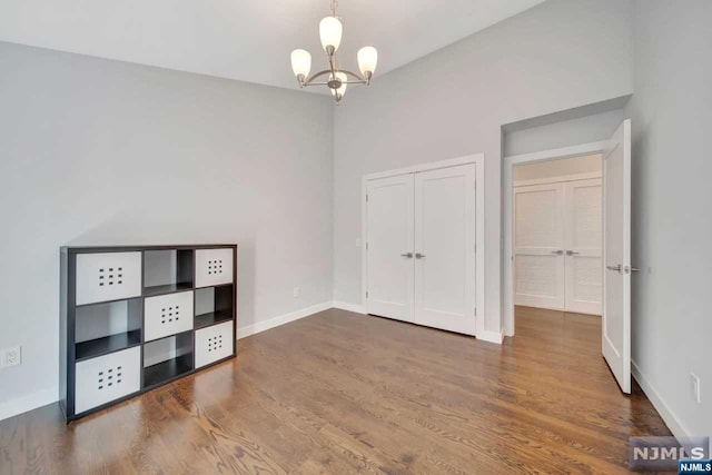 unfurnished bedroom featuring a closet, dark hardwood / wood-style flooring, and an inviting chandelier