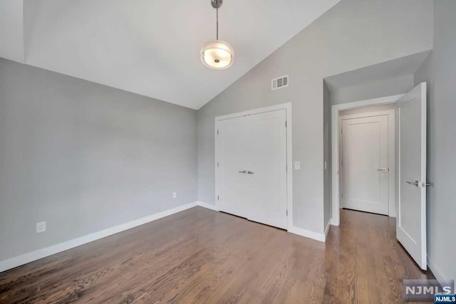 unfurnished bedroom featuring dark wood-type flooring and high vaulted ceiling