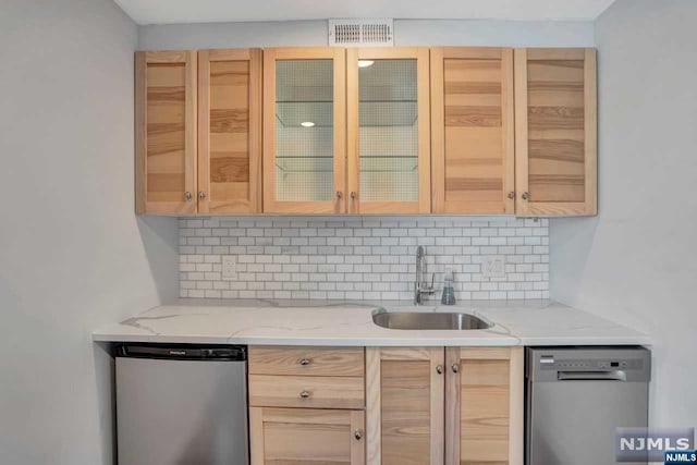 kitchen with decorative backsplash, light brown cabinets, stainless steel dishwasher, and sink