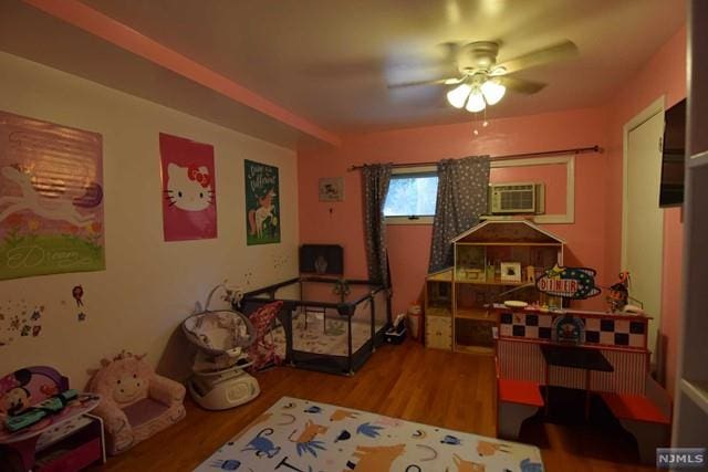 interior space featuring hardwood / wood-style floors, a wall unit AC, and ceiling fan