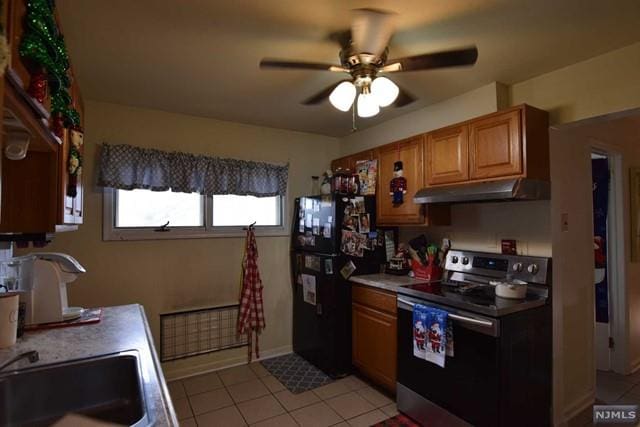 kitchen featuring black refrigerator, sink, ceiling fan, stainless steel electric range oven, and light tile patterned floors