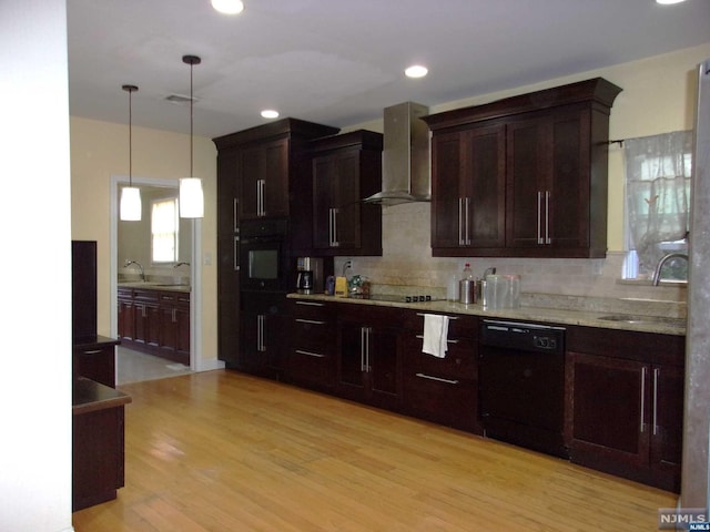 kitchen featuring a sink, light wood-style floors, black appliances, wall chimney exhaust hood, and tasteful backsplash