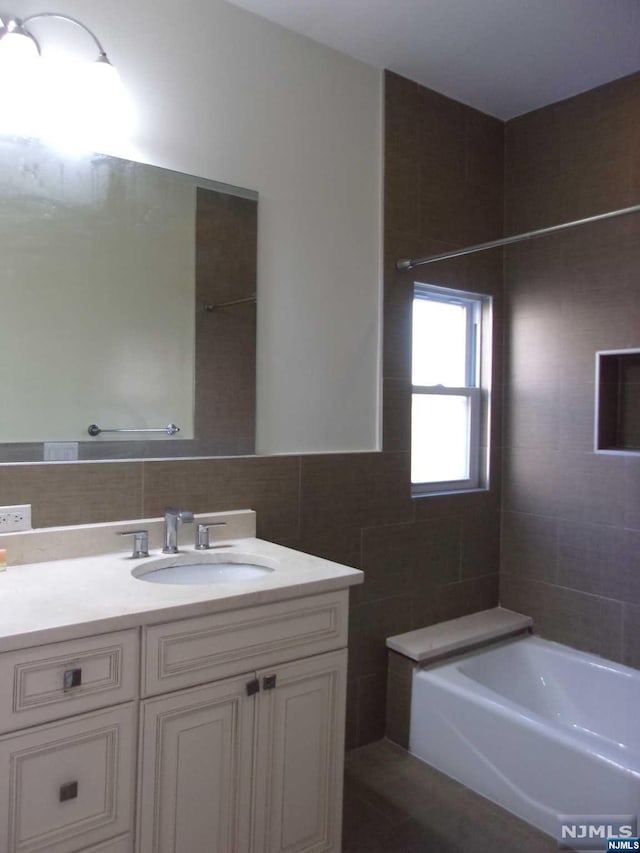 full bath featuring a tub, tile walls, and vanity