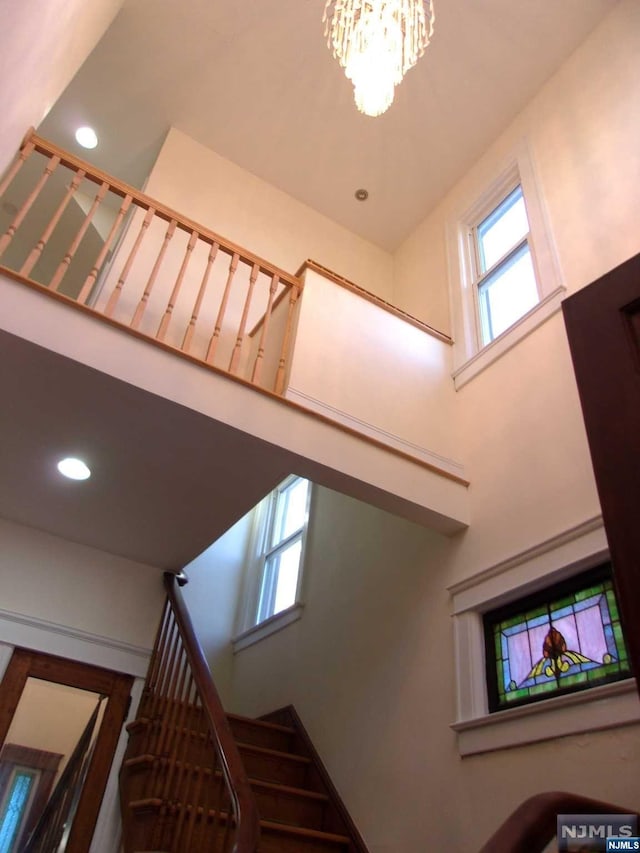 stairs with a chandelier, a towering ceiling, and recessed lighting