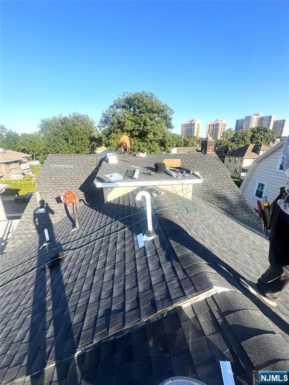 details with a shingled roof and a view of city