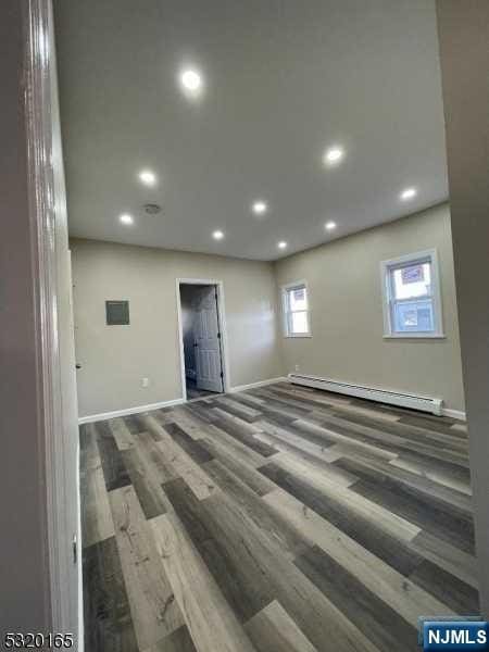 empty room featuring baseboard heating and dark wood-type flooring