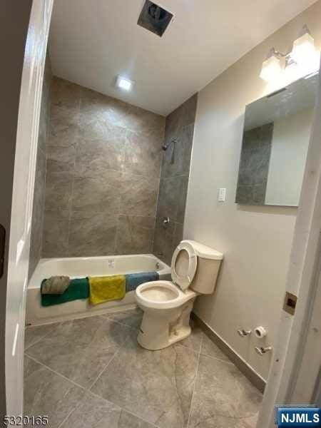 bathroom featuring toilet and tiled shower / bath