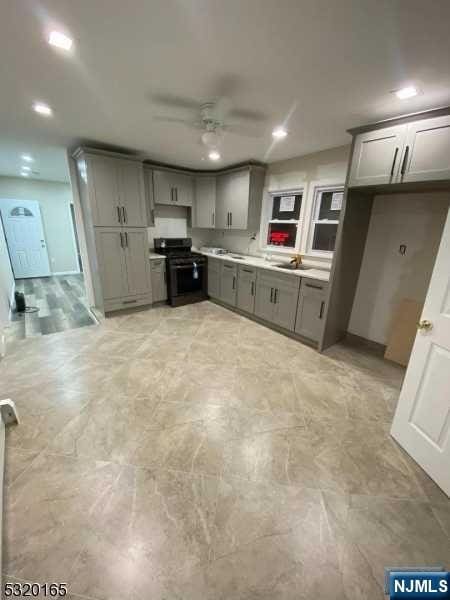 kitchen featuring black / electric stove, ceiling fan, sink, and gray cabinetry