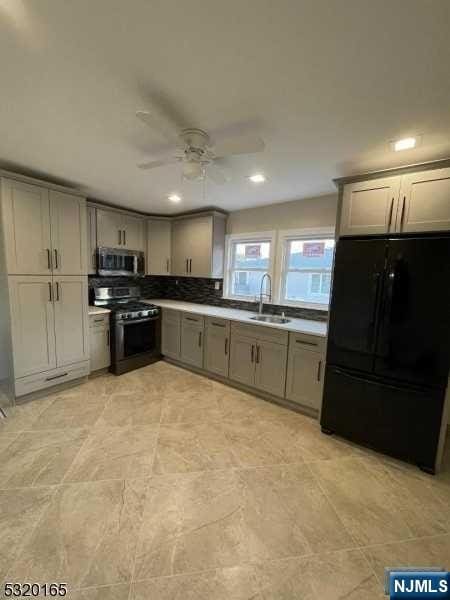 kitchen featuring stainless steel appliances, ceiling fan, gray cabinetry, and sink