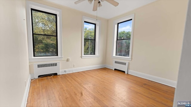 spare room featuring a healthy amount of sunlight, light hardwood / wood-style floors, and radiator