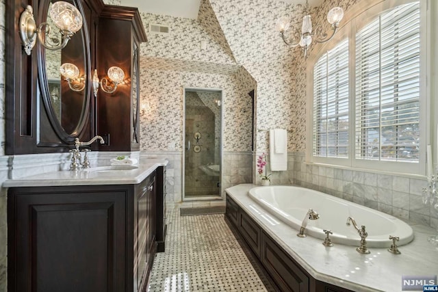 bathroom featuring vanity, vaulted ceiling, tile walls, independent shower and bath, and a chandelier