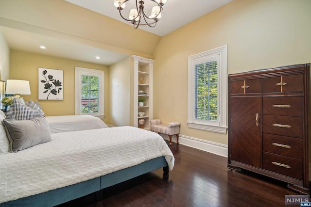 bedroom with an inviting chandelier, dark wood-type flooring, and vaulted ceiling