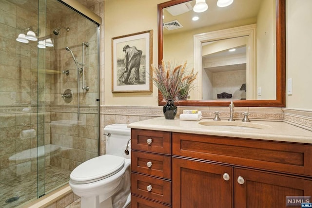 bathroom featuring tile walls, vanity, an enclosed shower, and toilet