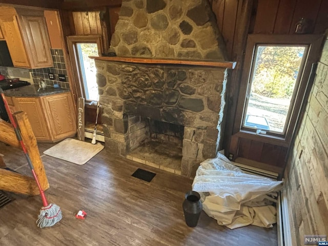 living room with baseboard heating, a fireplace, wood walls, and dark hardwood / wood-style flooring