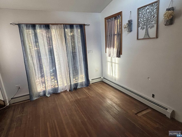 empty room with hardwood / wood-style floors, a baseboard radiator, and vaulted ceiling