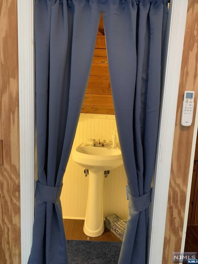 bathroom with wood walls and hardwood / wood-style flooring