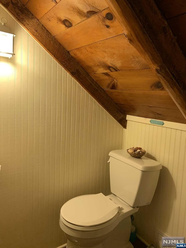 bathroom with toilet, wooden ceiling, and wooden walls