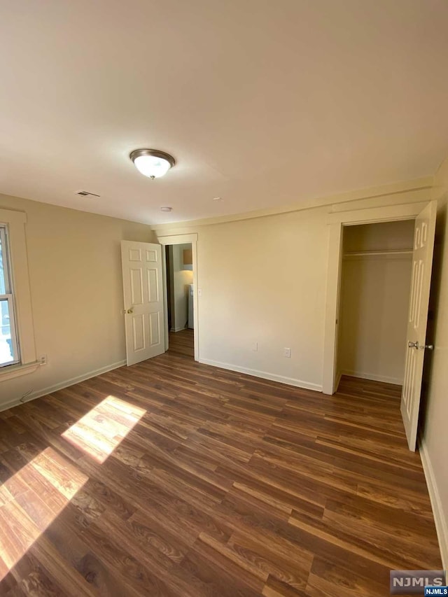 unfurnished bedroom with dark hardwood / wood-style flooring and a closet