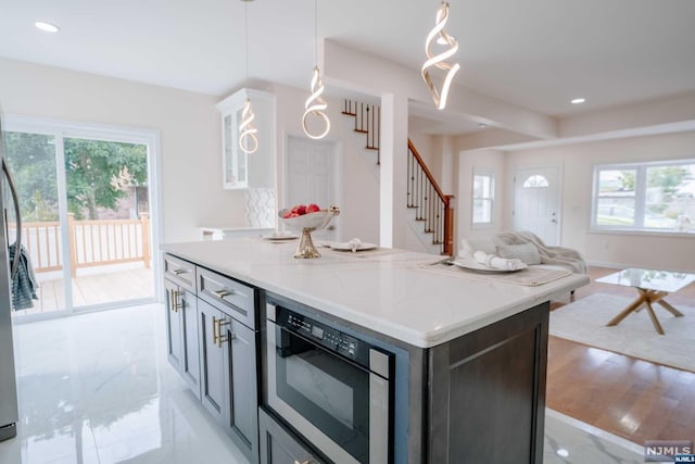 kitchen with light stone countertops, a center island, hanging light fixtures, and light hardwood / wood-style floors