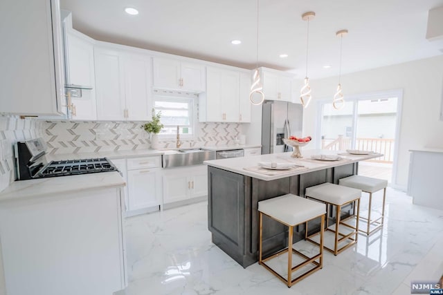 kitchen featuring decorative backsplash, decorative light fixtures, a kitchen island, white cabinetry, and stainless steel appliances