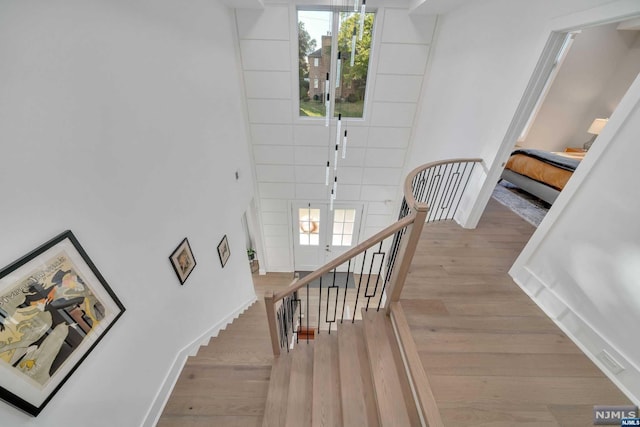 staircase with plenty of natural light, wood-type flooring, and french doors