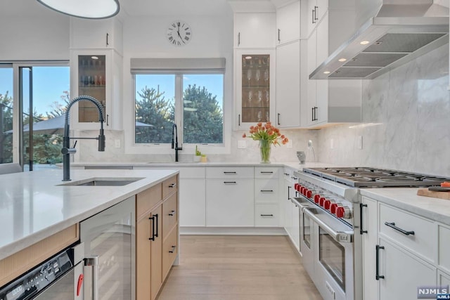 kitchen with a wealth of natural light, range with two ovens, beverage cooler, and wall chimney range hood