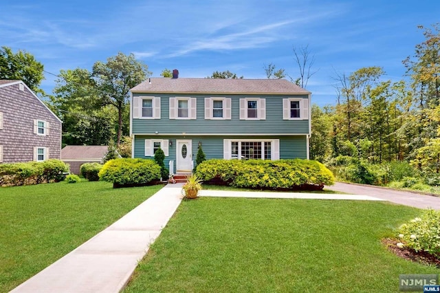 colonial-style house featuring a front lawn