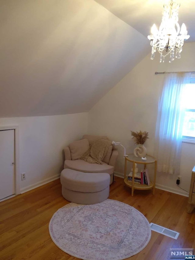 living area with wood-type flooring, vaulted ceiling, and a notable chandelier