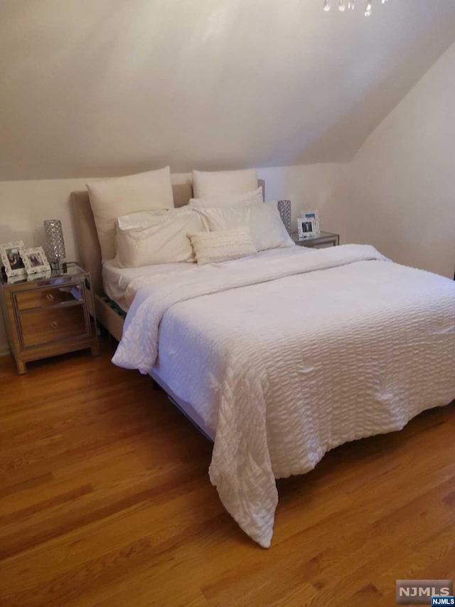 bedroom with wood-type flooring and lofted ceiling