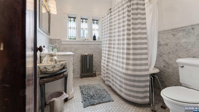 bathroom featuring tile patterned floors, sink, tile walls, radiator heating unit, and toilet