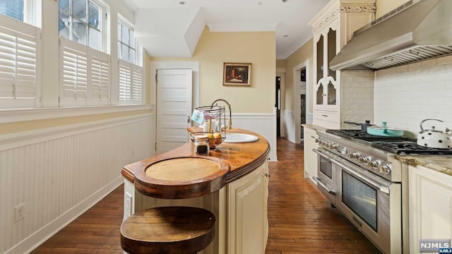 kitchen with decorative backsplash, dark hardwood / wood-style flooring, double oven range, and wall chimney range hood