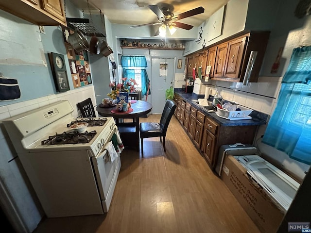 kitchen with sink, ceiling fan, tasteful backsplash, wood-type flooring, and white range with gas cooktop