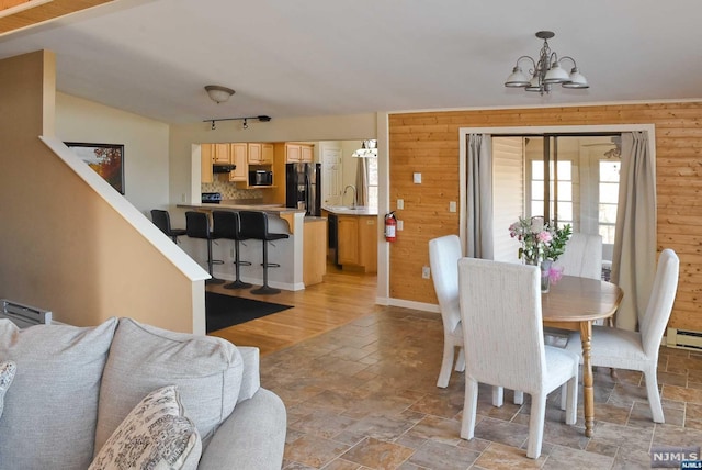 dining space with light hardwood / wood-style floors, a notable chandelier, and wood walls