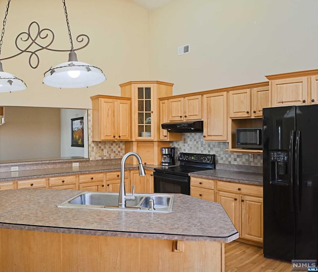 kitchen with tasteful backsplash, sink, black appliances, light hardwood / wood-style flooring, and hanging light fixtures