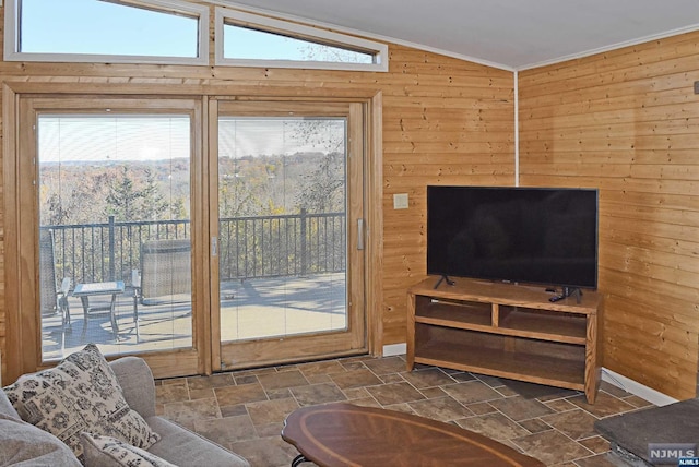 living room with vaulted ceiling, ornamental molding, and wood walls